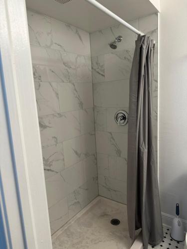 霍姆斯泰德The Hotel Redland的配有白色大理石墙壁和淋浴帘的淋浴间
