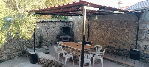 PelahustánCasa Rural La Fragua de Manuel的庭院设有木桌、椅子和石墙