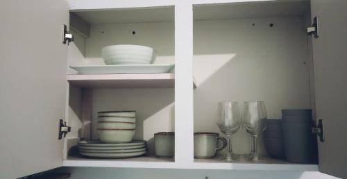 圣胡安Urban Lodgings Two @ Roosevelt 457的白色的橱柜,有盘子和玻璃杯,盘子