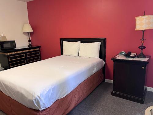 威利斯顿Ramada by Wyndham Williston的一间卧室设有一张床和红色的墙壁