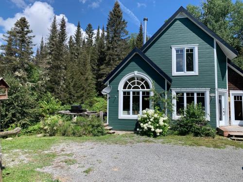 拉马巴耶Le Ti Moose - Les Chalets Spa Canada的绿色房子,设有白色窗户