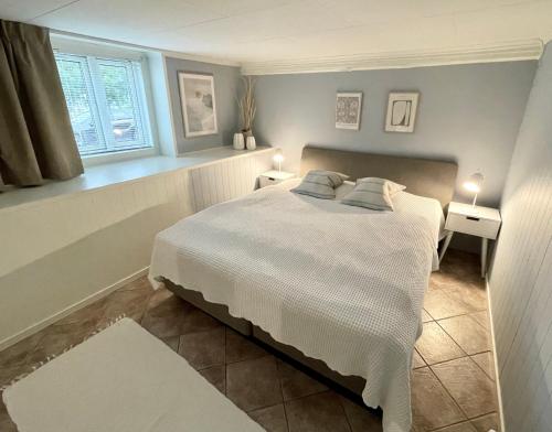 特罗姆瑟One bedroom basement apartment in the city的卧室配有白色的床和窗户。