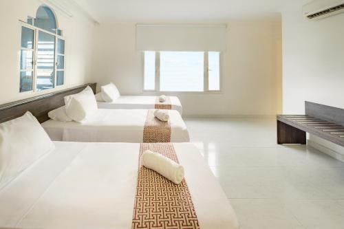 圣安德烈斯Hotel Americas San Andres Islas Colombia的白色客房的两张床,配有钢琴