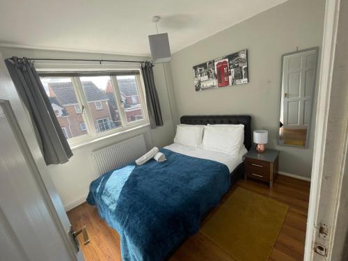 奥尔德伯里FilmonHomes的一间卧室配有一张带蓝色毯子的床和窗户。