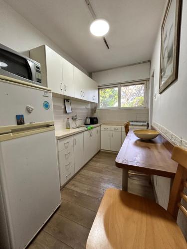 海法3-х комнатная квартира у моря в Хайфе的厨房配有白色橱柜和木桌