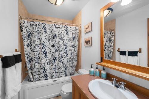 蒙特朗布朗Les Falaises Tremblant - Ski Inout Condo W2bdrs的一间带水槽和淋浴帘的浴室
