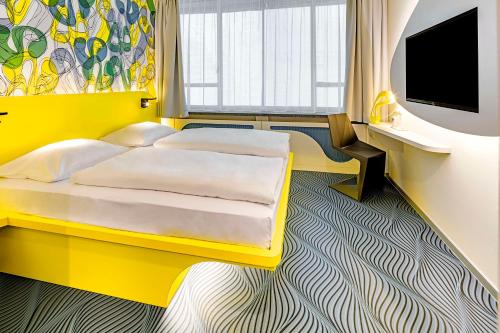 多特蒙德prizeotel Dortmund-City的黄色卧室设有床和平面电视