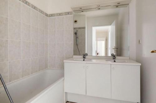 丰特奈苏布瓦Grand appartement en face du RER A, Parking, Paris 20 mn, Disneyland 40 mn的白色的浴室设有浴缸和水槽。