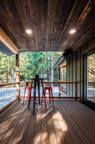 莱文沃思Ski Chalet A cozy little cabin in the woods near Lake Wenatchee的甲板上配有桌椅的门廊