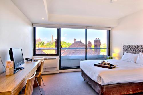 墨尔本四季墨尔本文化遗址酒店的一间卧室配有一张床、一张书桌和一个窗户。