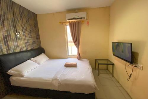 秾莎OYO 92932 Guesthouse Marbella的一间卧室设有一张床、一个窗口和一台电视