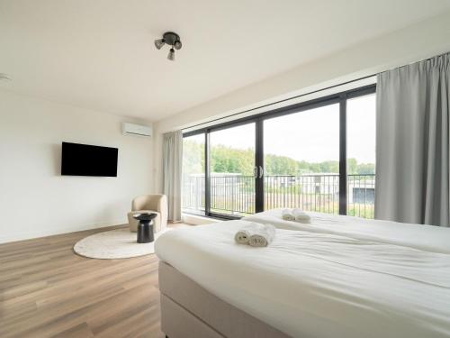 泽沃德Cosy, modern family villa up to 6p in Flevoland in a wonderful environment的一间卧室设有一张大床和一个大窗户