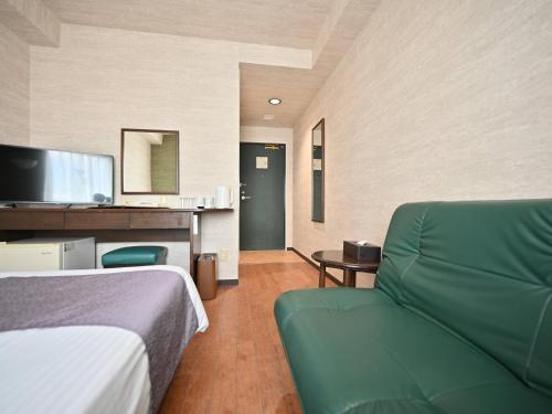 石垣岛ホテルアビアンパナ石垣島的酒店客房,设有一张床铺和一张绿色沙发