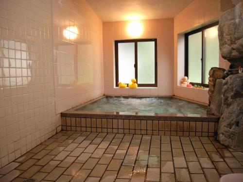 白川村Oyado Yunosato的带2扇窗户和热水浴池的浴室