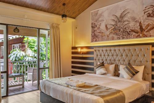 莫尔吉姆Skon Morjim Beach Resort by Orion Hotels的一间带大床的卧室和一个阳台