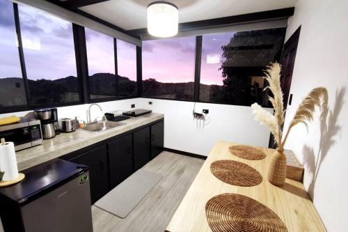 蒙泰韦尔德哥斯达黎加Calma, Monteverde - Expect Serenity Here的厨房配有木桌和一些窗户。