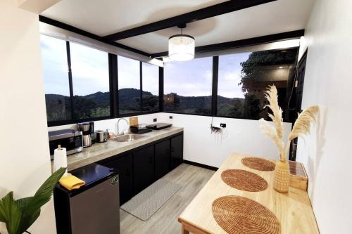 蒙泰韦尔德哥斯达黎加Calma, Monteverde - Expect Serenity Here的厨房配有桌子和一些窗户。
