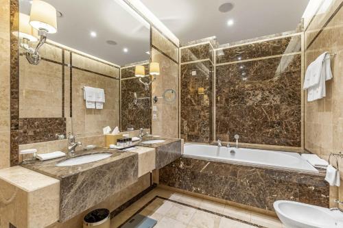 基辅Khreschatyk Hotel的浴室配有2个盥洗盆、浴缸和淋浴。