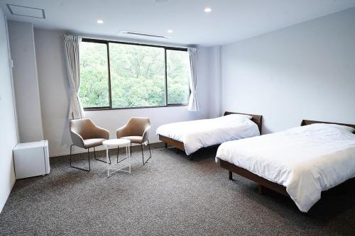 日向OiseSun CAFE & HOTEL的客房设有两张床、两把椅子和窗户。