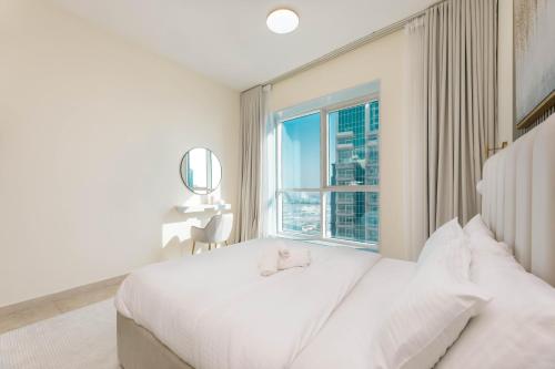 迪拜Charming Condo With Balcony In The Heart of JLT的卧室配有白色的床和窗户。