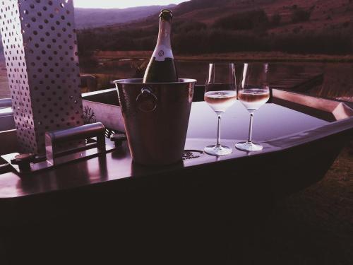 德尔斯特鲁姆African Leaves Trout Lodge的桌子上放有一瓶葡萄酒和两杯酒