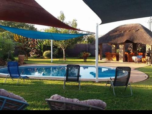 维多利亚瀑布Room in Villa - Zambezi Family Lodge - Elephant Room的一个带椅子的庭院和一个带遮阳伞的游泳池