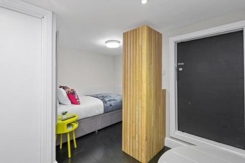 伦敦Unique single occupancy studio的卧室配有床和窗边的黄色椅子