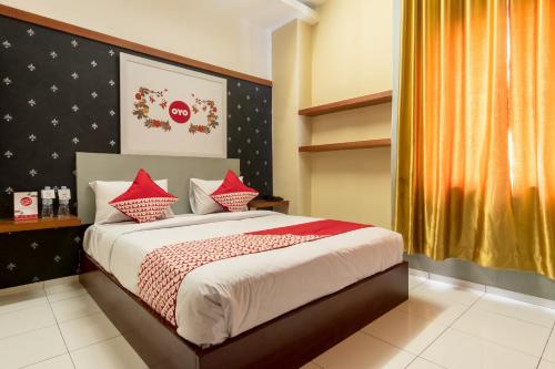 棉兰Capital O 615 Residence Puri Hotel Syariah的一间卧室配有一张带红色枕头的大床