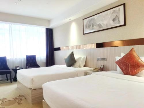 广州Paco Hotel Tianhe Coach Terminal Metro Guangzhou的酒店客房配有两张床和一张书桌