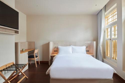 新加坡KINN Studios的卧室配有一张白色大床和一张书桌