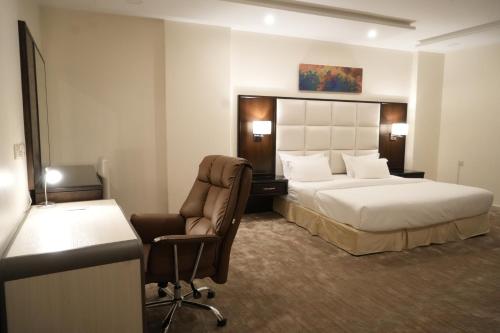 艾卜哈فندق رحيب للشقق المخدومة Rahib Suites的酒店客房配有一张床、一张桌子和一把椅子。