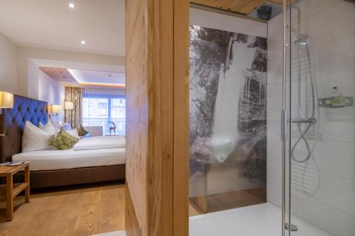 伊施格尔奥林匹亚酒店的一间卧室设有一张床和一个玻璃淋浴间