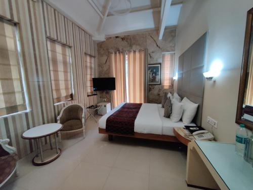 孟买Capital Hotel的大型酒店客房设有一张床铺和一张桌子。