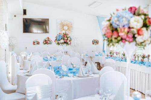 瓦赫河畔新梅斯托Penzion Adriana的一间设有白色桌子和白色椅子及鲜花的房间