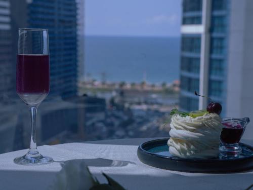 巴统New Wave Hotel的一张桌子,上面放着一盘食物和一杯葡萄酒