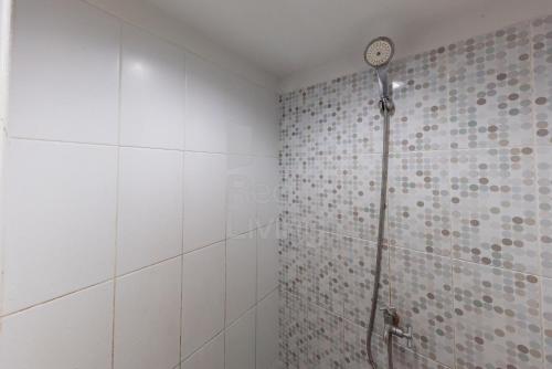 加拉旺RedLiving Apartemen Grand Sentraland - Dragon Apartel Tower Pink的带淋浴的浴室,墙上有时钟