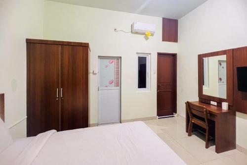 棉兰Teratai Residence Mitra RedDoorz的一间卧室配有一张床、一张书桌和一台电视