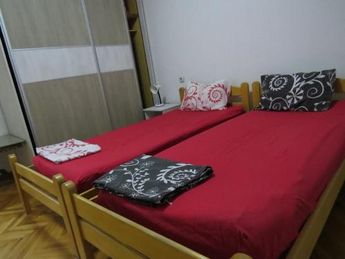 斯科普里SKOPJE REKORD APARTMENT的一间卧室配有两张带红色床单和枕头的床。