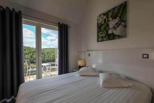 讷沙托Hotel Bô Rivage -- Eden-Ardenne的一间卧室设有一张床和一个美景窗户。
