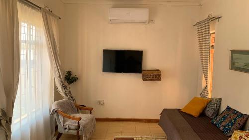 卡萨内Plateau Home的客厅配有沙发和墙上的电视
