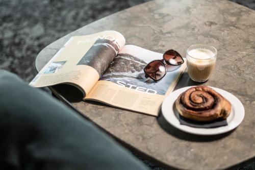 哥本哈根Go Hotel Østerport的一本书,一杯咖啡和一张桌子上的糕点