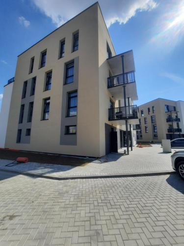 帕内韦日斯Ainių gatvės apartamentai的一座白色的大建筑,前面有停车位