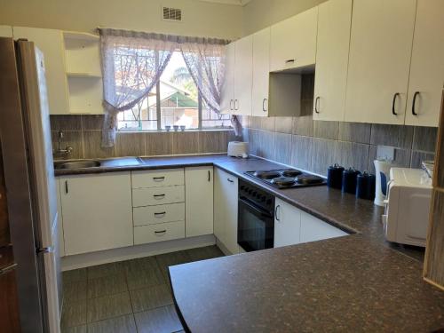 波罗瓜尼29B Zebra Street - InHimwe Guesthouse的厨房配有白色橱柜和炉灶烤箱。