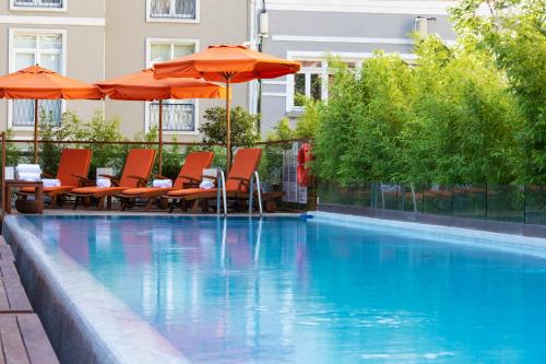 伊斯坦布尔伊斯坦布尔凯悦公园酒店 - 马茨卡帕拉斯的一个带橙色遮阳伞和桌椅的游泳池