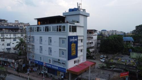 迪布鲁加尔CENTRAL INN的白色的建筑,上面有蓝色和黄色的标志