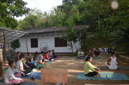 马特莱Spiritual Nature Farm - Sri Lanka的一群人坐在房子前面的垫子上