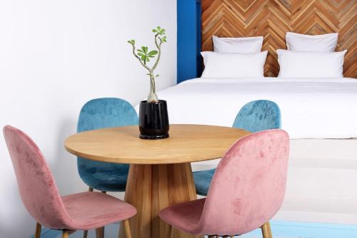 恰洛克拉姆Adika - The beachfront Loft的一张带粉红色椅子的桌子和一张床