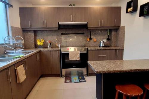 洛哈Bonita casa en sector residencial al norte de Loja的厨房配有木制橱柜和炉灶烤箱。