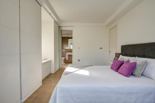 伦敦Chic 1BR Central London Retreat的白色卧室配有一张带紫色枕头的大床