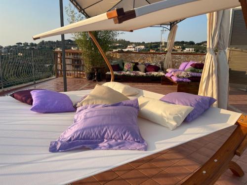 巴科利DOMUS PARVA - Villa con bio-piscina, spa privata e appartamenti panoramici的阳台的一张带紫色和白色枕头的床